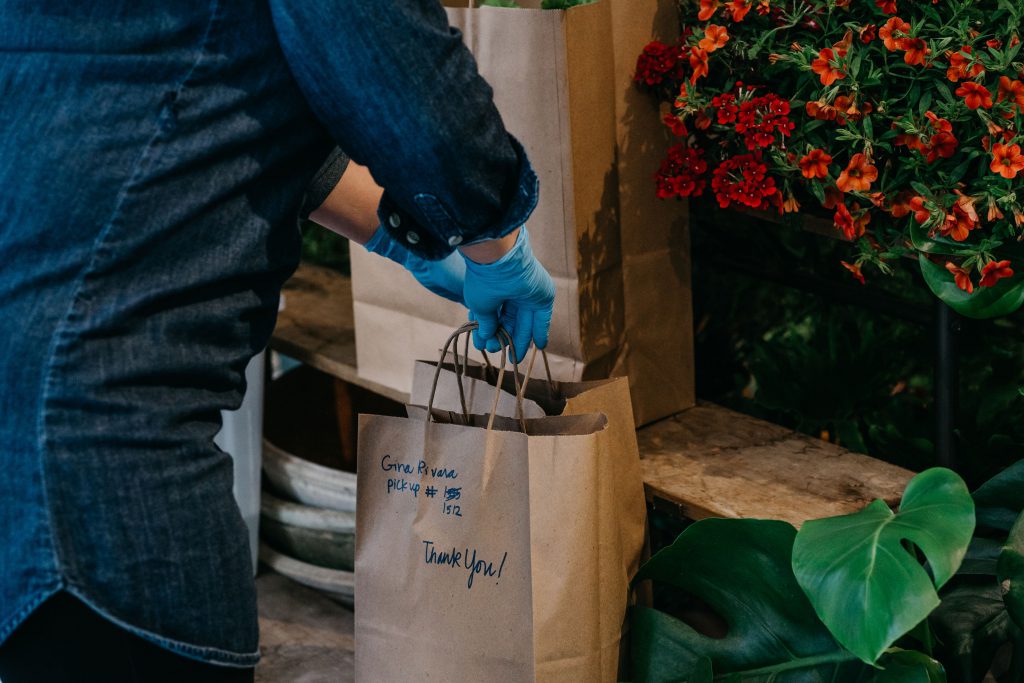 a person places two brown paper bags down on a stoop