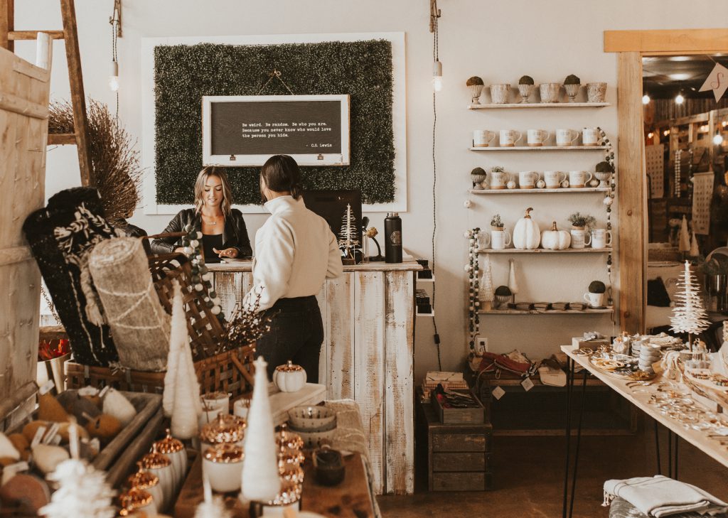 a customer in a white sweater is checking out in a rustic small store decorated for the holidays