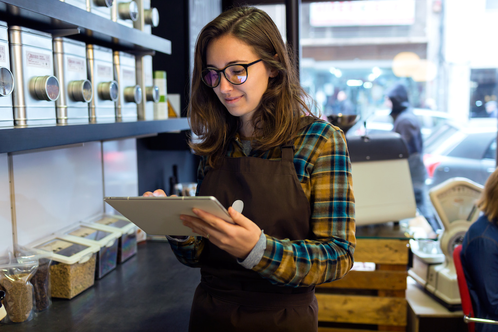 A woman takes inventory inside of an independent retail store that sells coffee