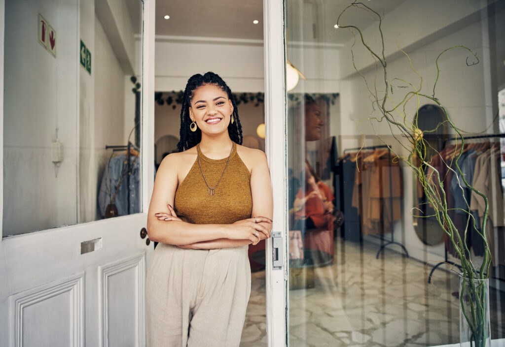 smiling shopkeeper leaning in the front door of her shop