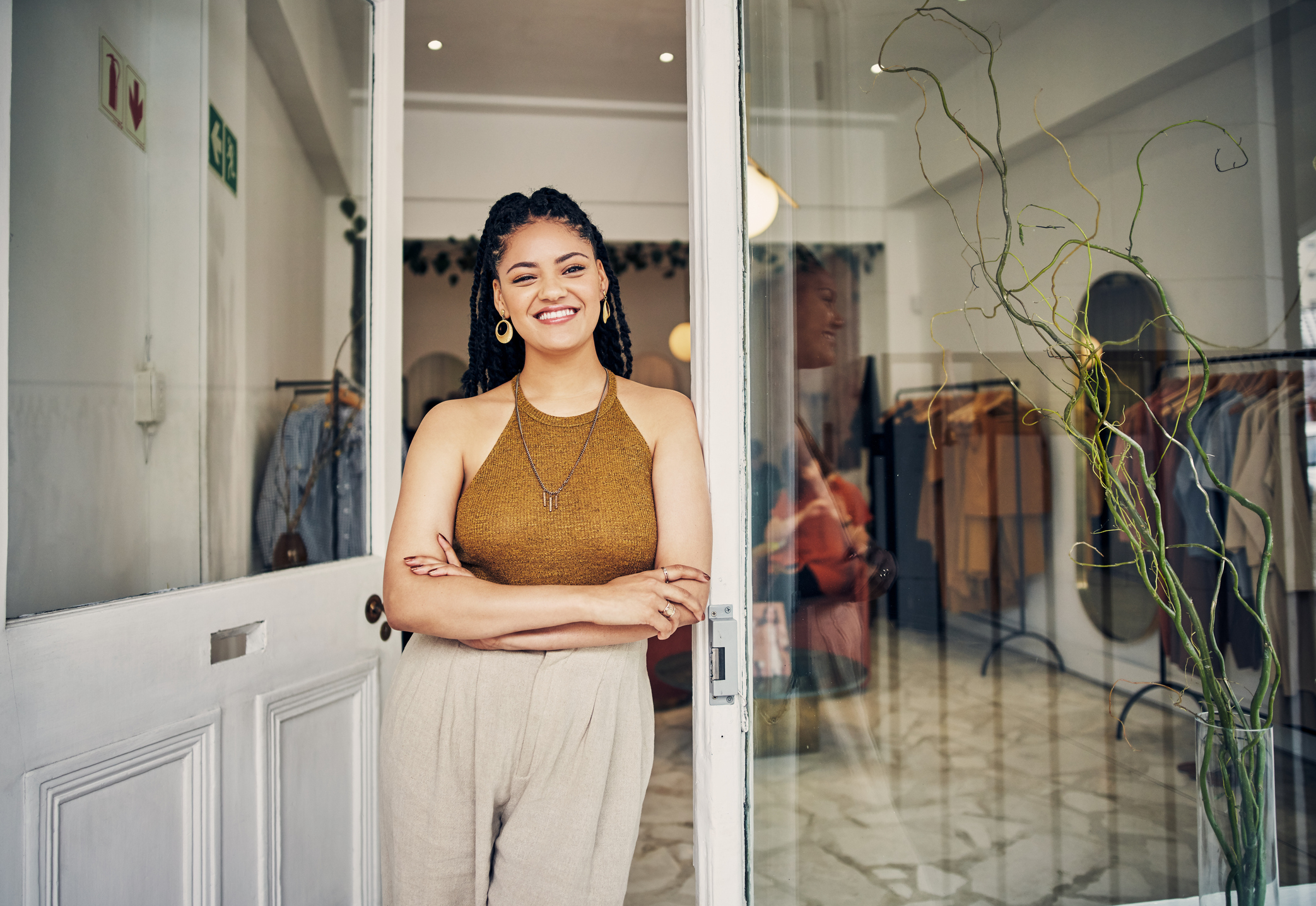 smiling shopkeeper leaning in the front door of her shop