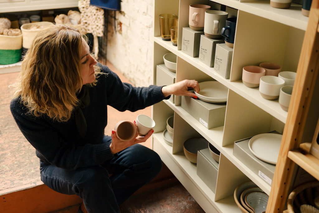 A shop owner fills her shelves with fresh inventory