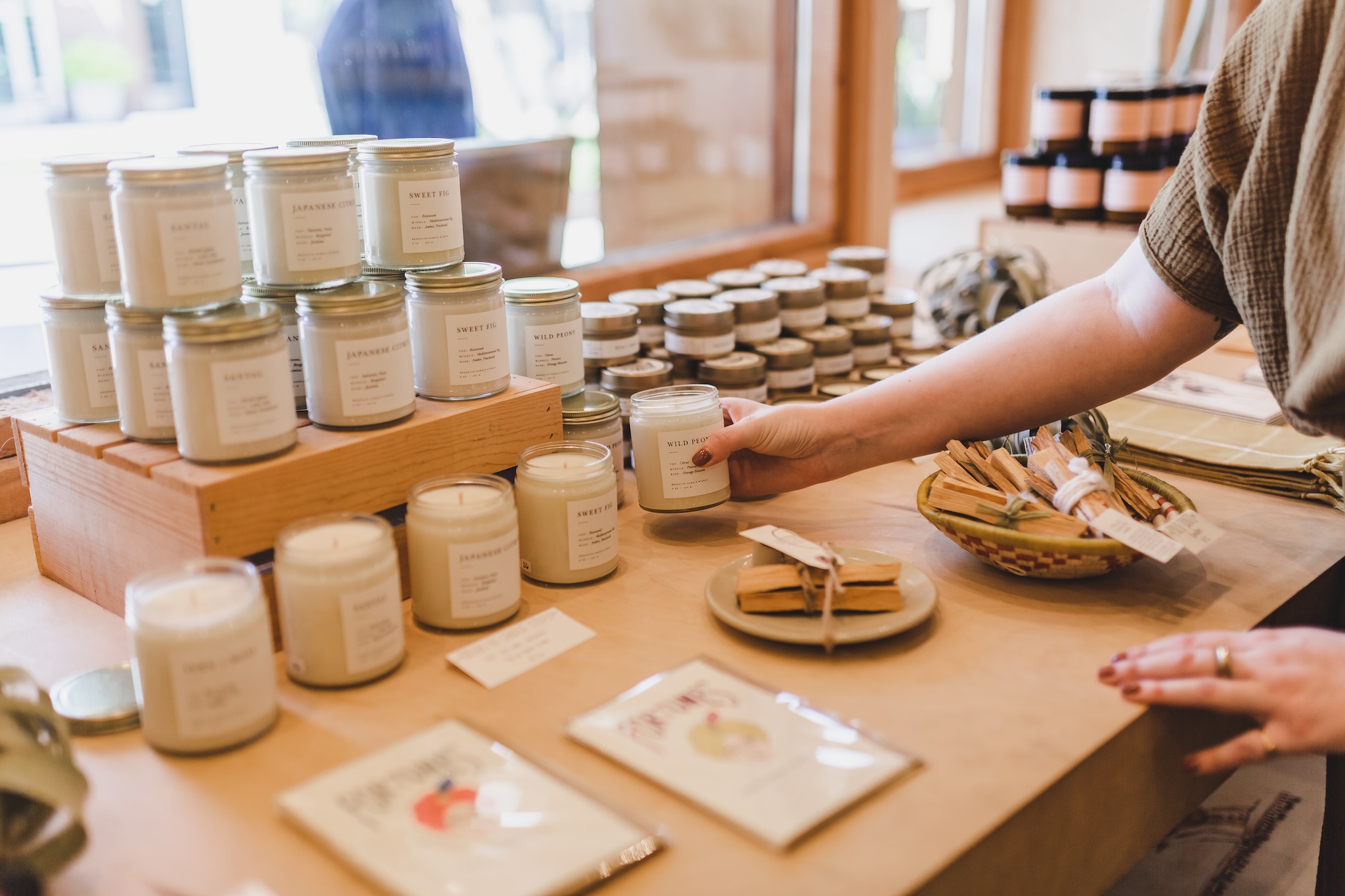 A retailer stocks a shelf with candles