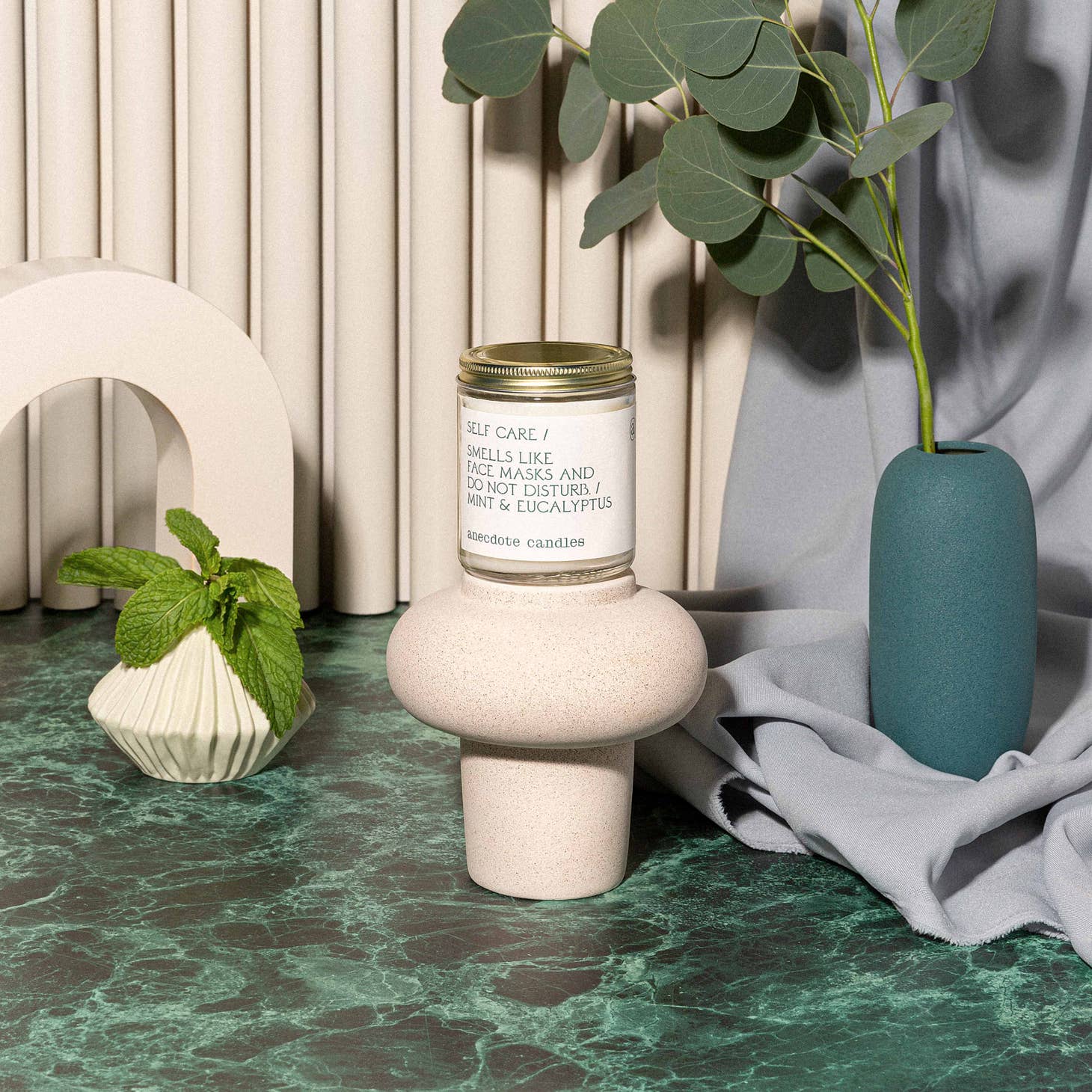 Small candle set on top of vase with lable Smells like face masks, do not disturb, and mint & eucalyptus.
