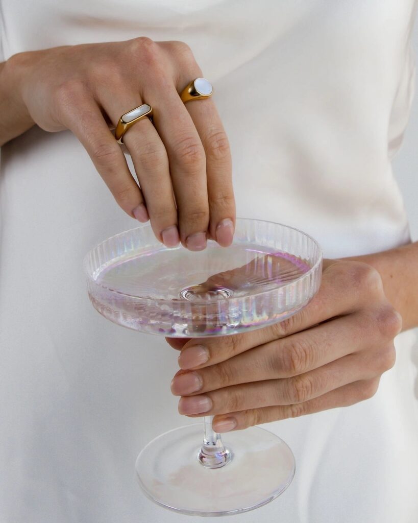 Woman holding a martini glass and showing off rings.