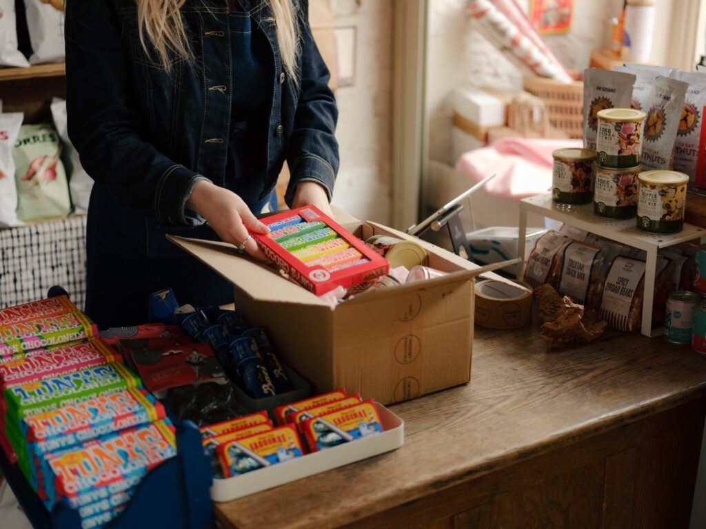 Retail employee packing bars of chocolate into a shipping box.