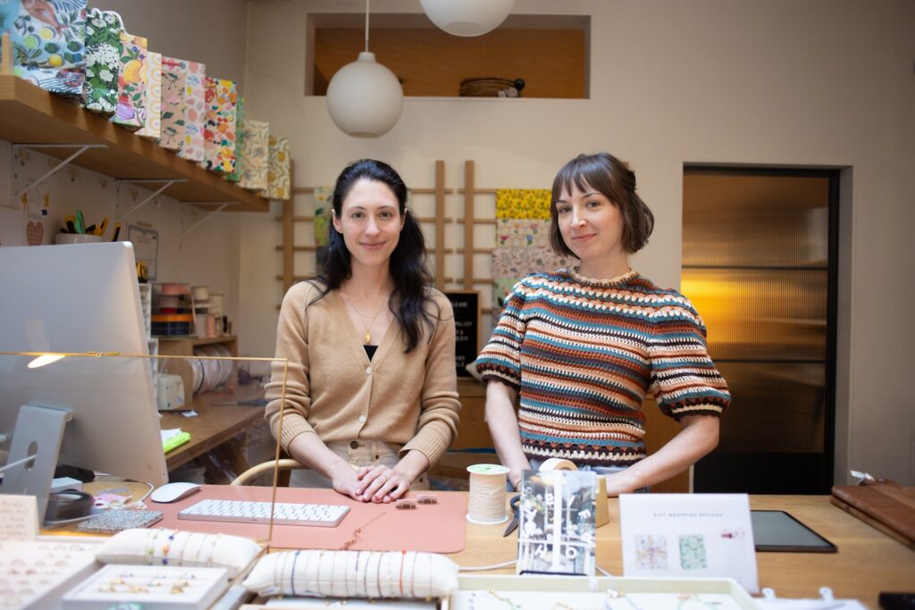 Two store owners posing in front of their cash register and computer.