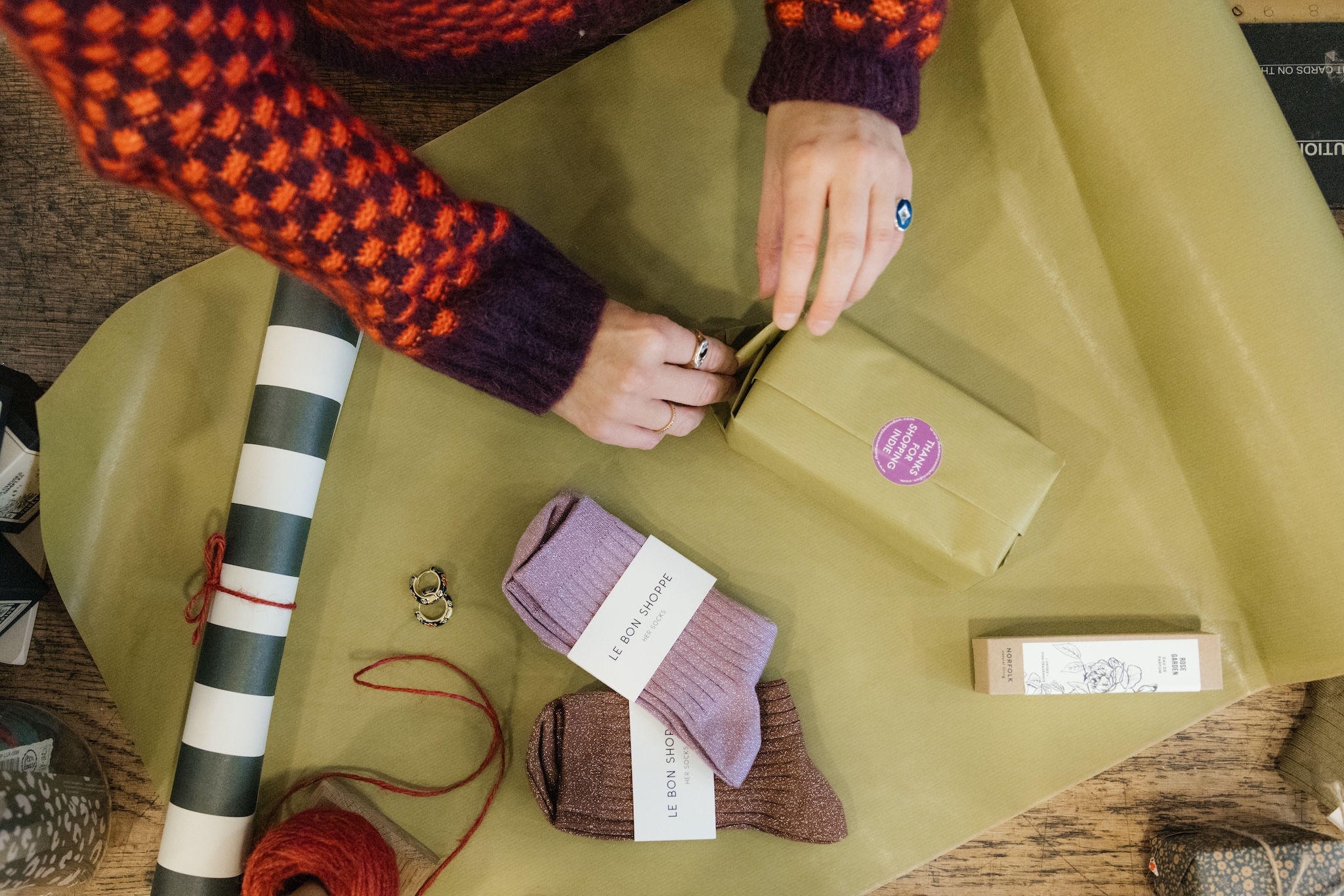 a shopkeeper's hands wrap socks and items in green tissue paper